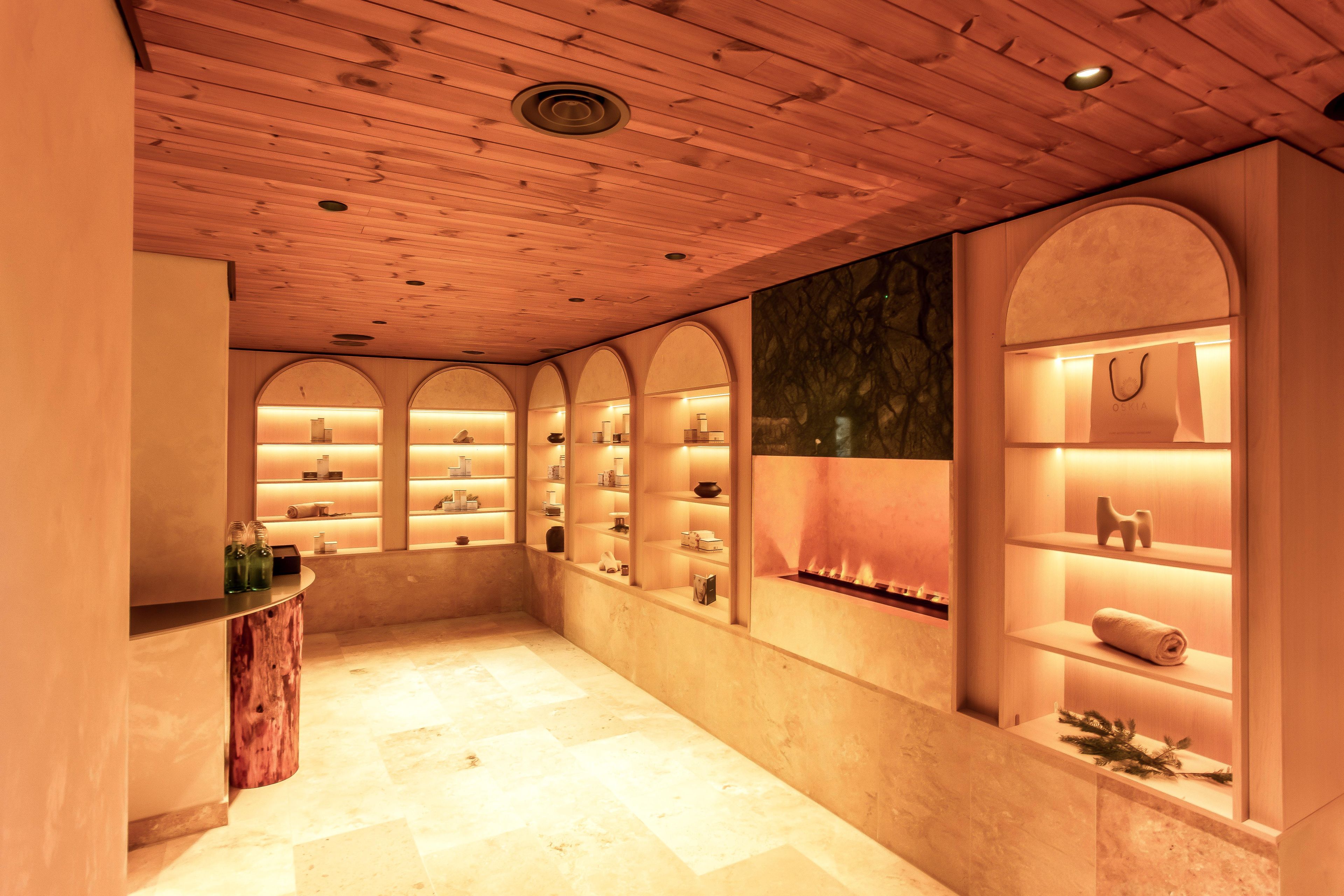 A spa-like interior with wooden paneling, arched shelving, and a central fireplace.
