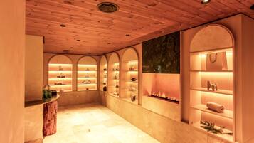 A spa-like interior with wooden paneling, arched shelving, and a central fireplace.