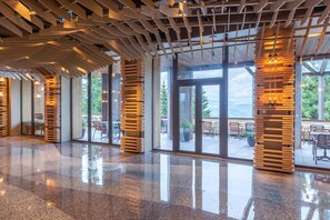 Un espacio interior amplio con piso pulido, ventanas grandes y elementos estructurales de madera.