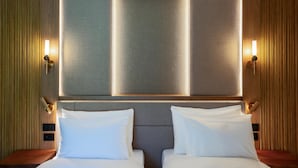 Habitación de hotel con una cama grande, dos mesitas de noche y un aplique de pared.