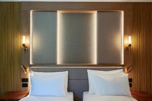 A hotel room with a large bed, two bedside tables, and a wall-mounted light fixture.