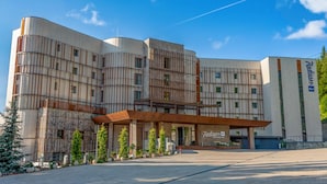 Un edificio moderno con fachada curva, un acceso cubierto y un cartel que indica que es un hotel Radisson.