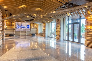 A spacious lobby with a modern design, featuring a prominent sign for Radisson Blu and a polished floor.
