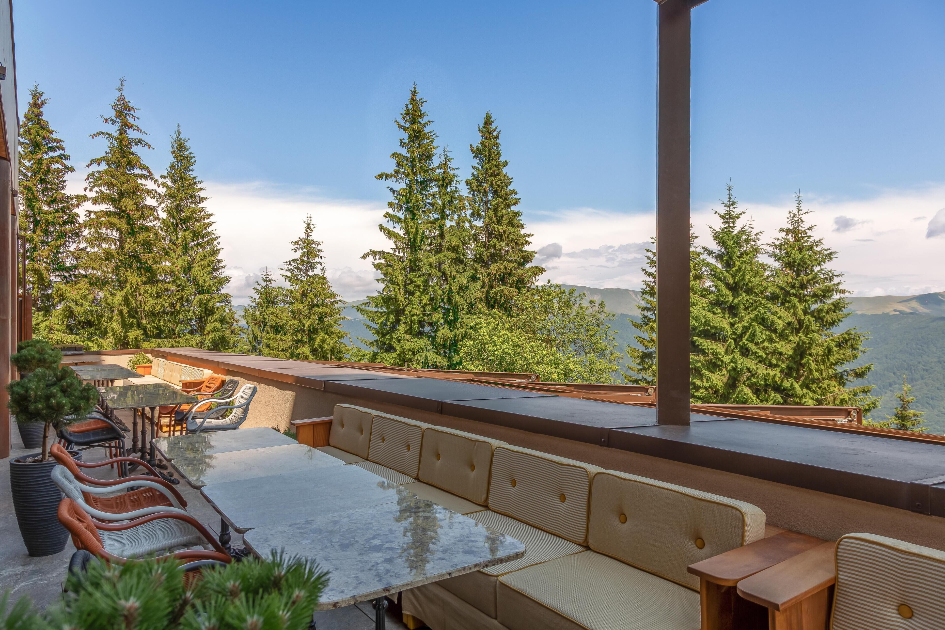 Una terraza con mesas al aire libre, con vistas a un paisaje montañoso.