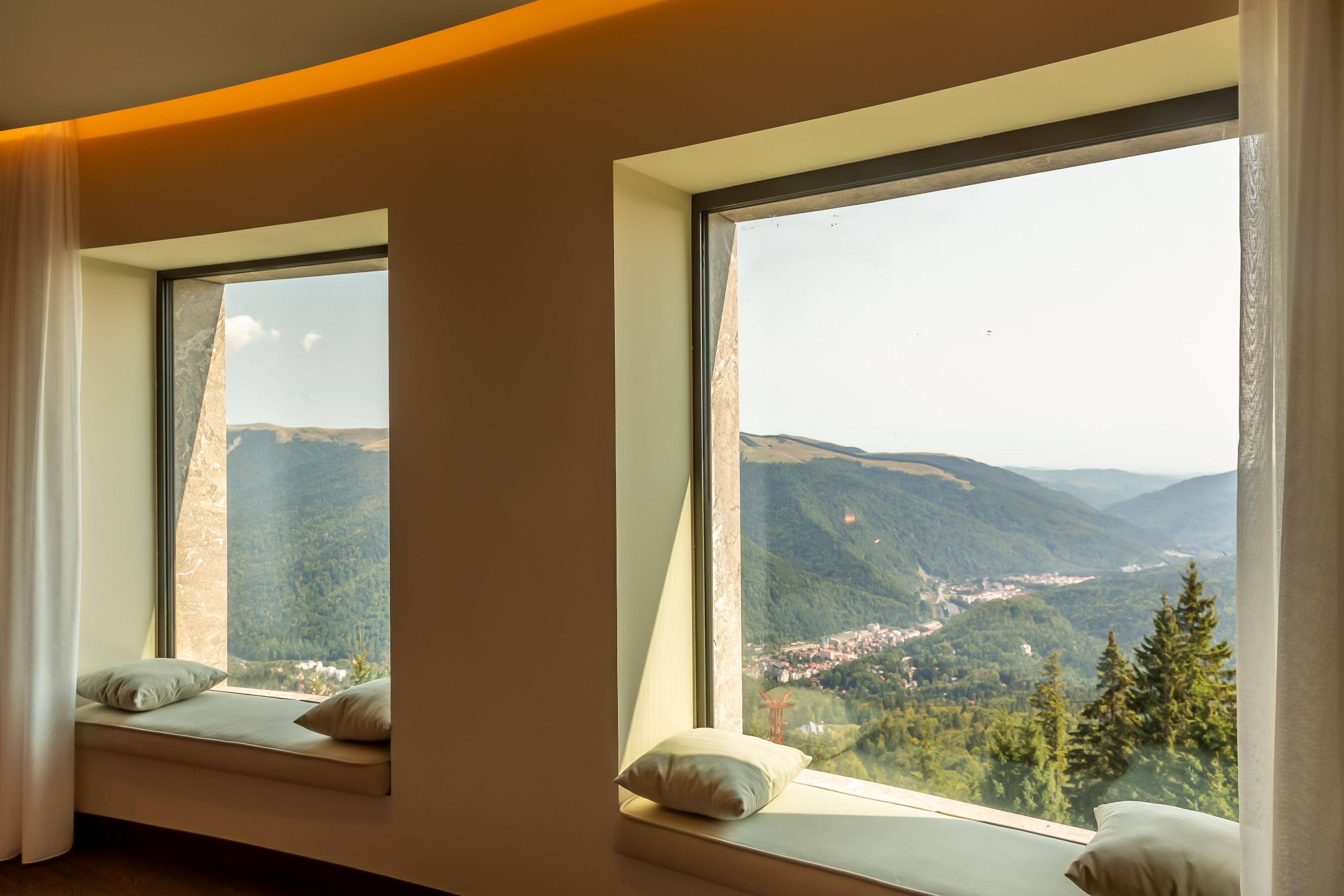 Una habitación con dos amplios ventanales que ofrecen vistas a un valle y montañas.