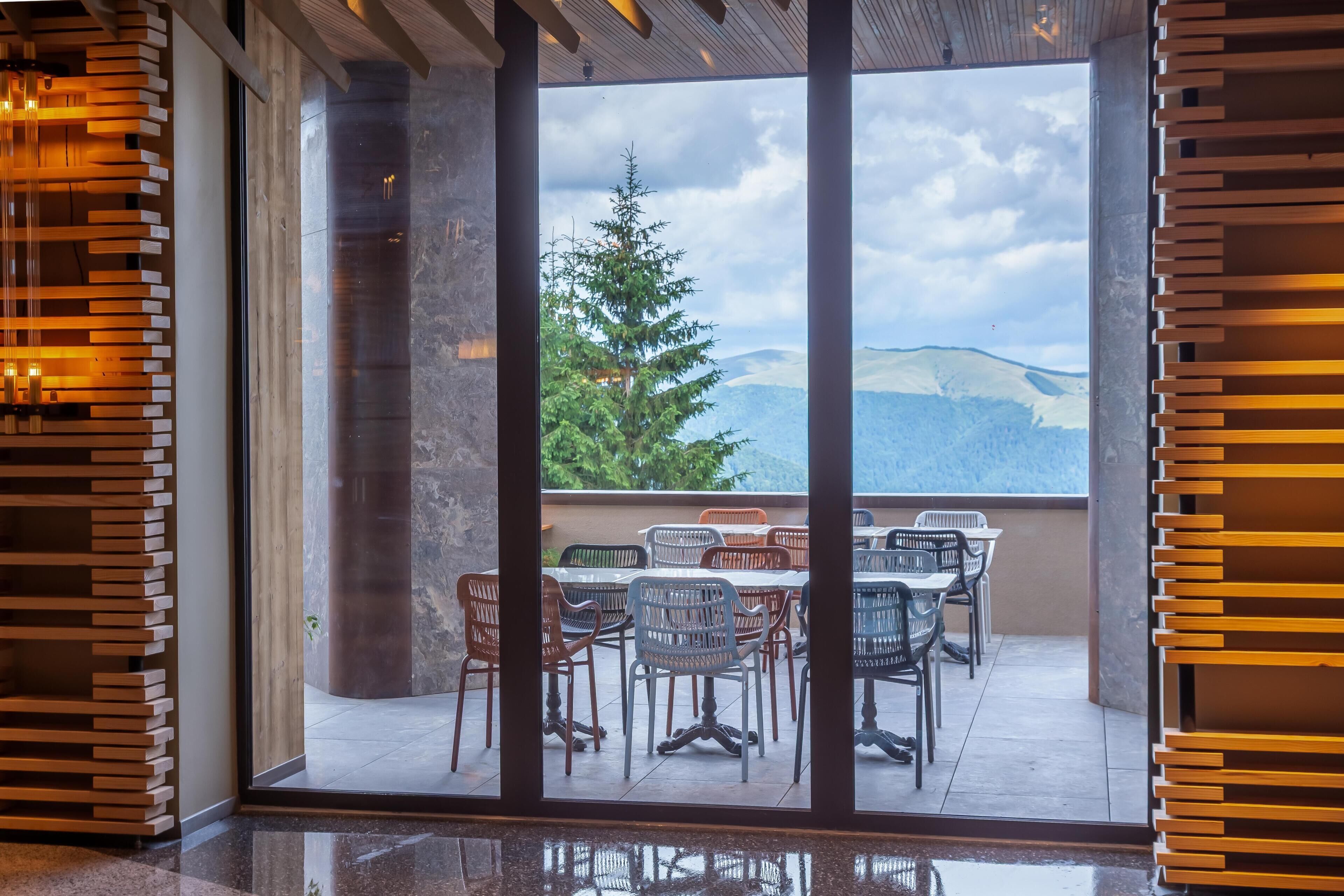 A modern interior with a view of a mountain landscape through large glass doors.