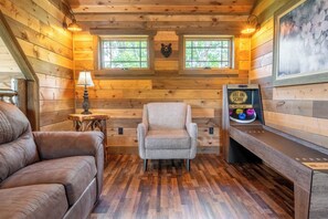 Interior acogedor de una cabaña con un sofá de cuero, un sillón mullido, una pequeña mesa de madera con una lámpara y un adorno de cabeza de oso montado en la pared.