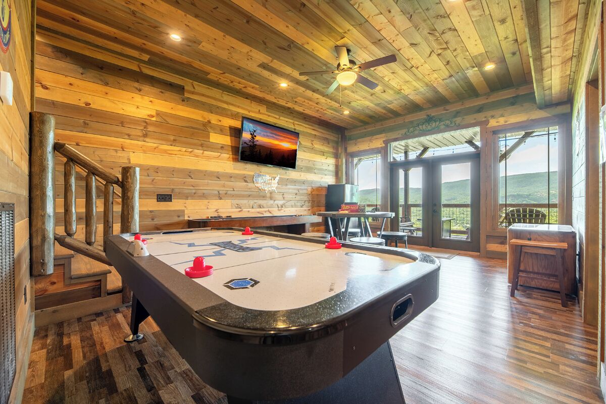 A pool table in a room with wooden walls and a ceiling fan.