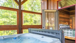 A hot tub in a cabin with a bed and a window overlooking greenery. - The Lodge at Coopers Hawk | Indoor Pool + Game Room & Hot Tub + VIEWS (Sevierville)