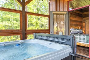 A hot tub in a cabin with a bed and a window overlooking greenery. - The Lodge at Coopers Hawk | Indoor Pool + Game Room & Hot Tub + VIEWS (Sevierville)