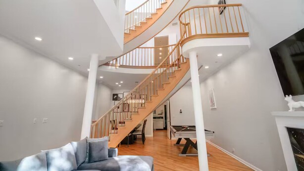 A spacious living area with a wooden staircase, a pool table, and a grey sofa. - Gold Coast Home - Rooftop - PoolTable - Parking - Views (Chicago)
