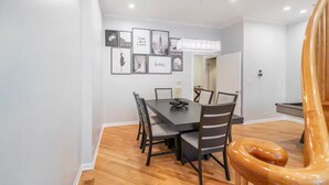 A dining area with a dark wooden table, six chairs, and a chandelier. - Gold Coast Home - Rooftop - PoolTable - Parking - Views (Chicago)