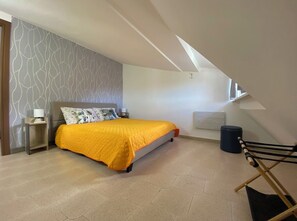A bedroom with a bed, a nightstand, a lamp, a window, and a ceiling with a sloped design. - Casa Maria della Rocca (Rocca d'Arce)