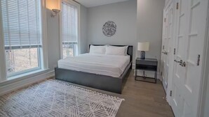 A bedroom with a bed, a nightstand, a lamp, a wall art piece, and a door. - Pristine Gold Coast 3BD - 2BA - Free Parking - Beach. (Chicago)
