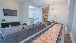 A living room with a large sofa, a coffee table, a flat-screen TV, and a dining area with chairs. - Pristine Gold Coast 3BD - 2BA - Free Parking - Beach. (Chicago)