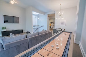 Un salon comprenant un grand canapé, une table basse, un téléviseur à écran plat et un coin repas avec des chaises.