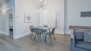 A modern dining area with a table and chairs, a chandelier, and artwork on the walls. - Pristine Gold Coast 3BD - 2BA - Free Parking - Beach. (Chicago)