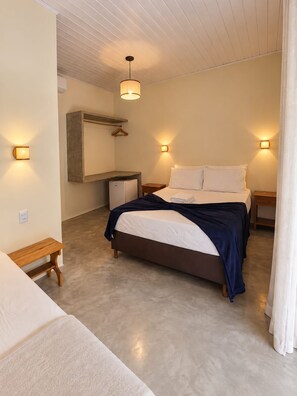 A bedroom with a bed, bedside tables, a hanging light fixture, and a small desk with a chair.