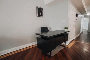 Un comedor moderno con una mesa de madera oscura, una sola silla negra y una pequeña planta en maceta en la pared.