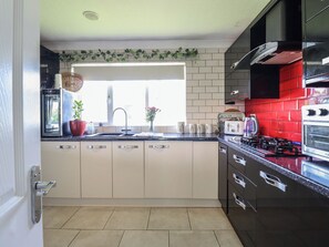 A modern kitchen with a sink, stove, and cabinets. - Excalabur 10 (Porthmadog)