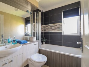 Een moderne badkamer met een wastafelmeubel, wastafel, spiegel en een bad.