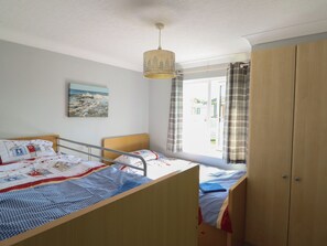 A bedroom with two beds, a window with curtains, a painting on the wall, and a wardrobe. - Excalabur 10 (Porthmadog)