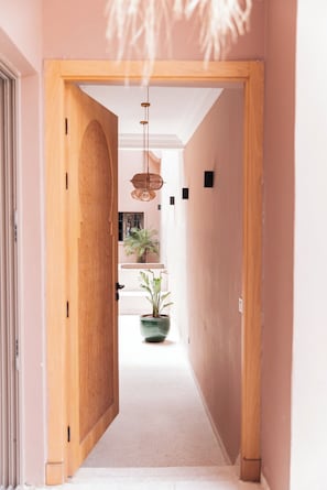 A hallway with a wooden door, a hanging light fixture, and a potted plant. - riad 16 art (Marrakech)