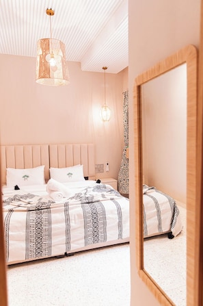 A hotel room with a large bed, a wooden headboard, a hanging light fixture, and a mirror on the wall. - riad 16 art (Marrakech)