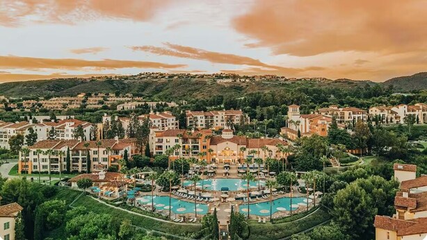 Un resort con diversi edifici, una piscina centrale e vegetazione circostante.