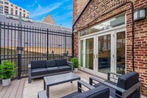 An outdoor patio with a black metal fence, a black sofa, and a table. - Gold Coast Pristine 5BR - 3.5BA - Patio - Parking (Chicago)