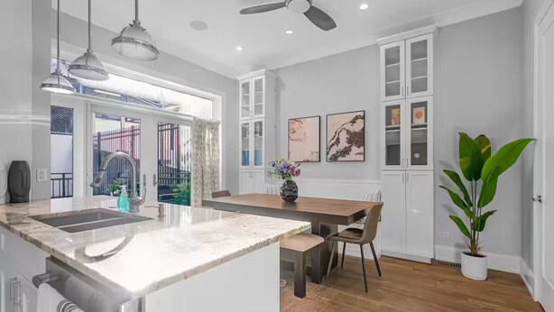 A modern kitchen with a marble island, pendant lights, ceiling fans, and a dining area with a table and chairs. - Gold Coast Pristine 5BR - 3.5BA - Patio - Parking (Chicago)