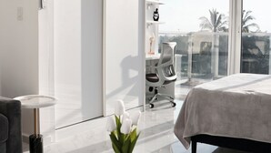 A modern bedroom with a large window, a bed, a desk, and a chair.