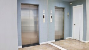 A hallway with two elevators and a door, all in a modern building.