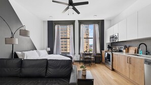 Un appartement moderne comprenant un lit, un coin repas, une cuisine et un ventilateur de plafond.