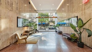 Un hall d’entrée spacieux avec un mur en verre, un coin salon et des plantes en pot.