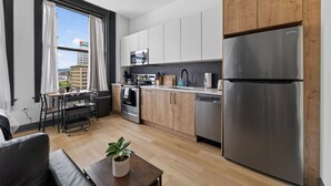 Une cuisine moderne équipée d’un réfrigérateur en acier inoxydable, de meubles en bois, d’un four à micro-ondes et d’un lave-vaisselle.