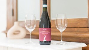 Une bouteille de vin avec une étiquette, deux verres à vin vides et une table blanche.