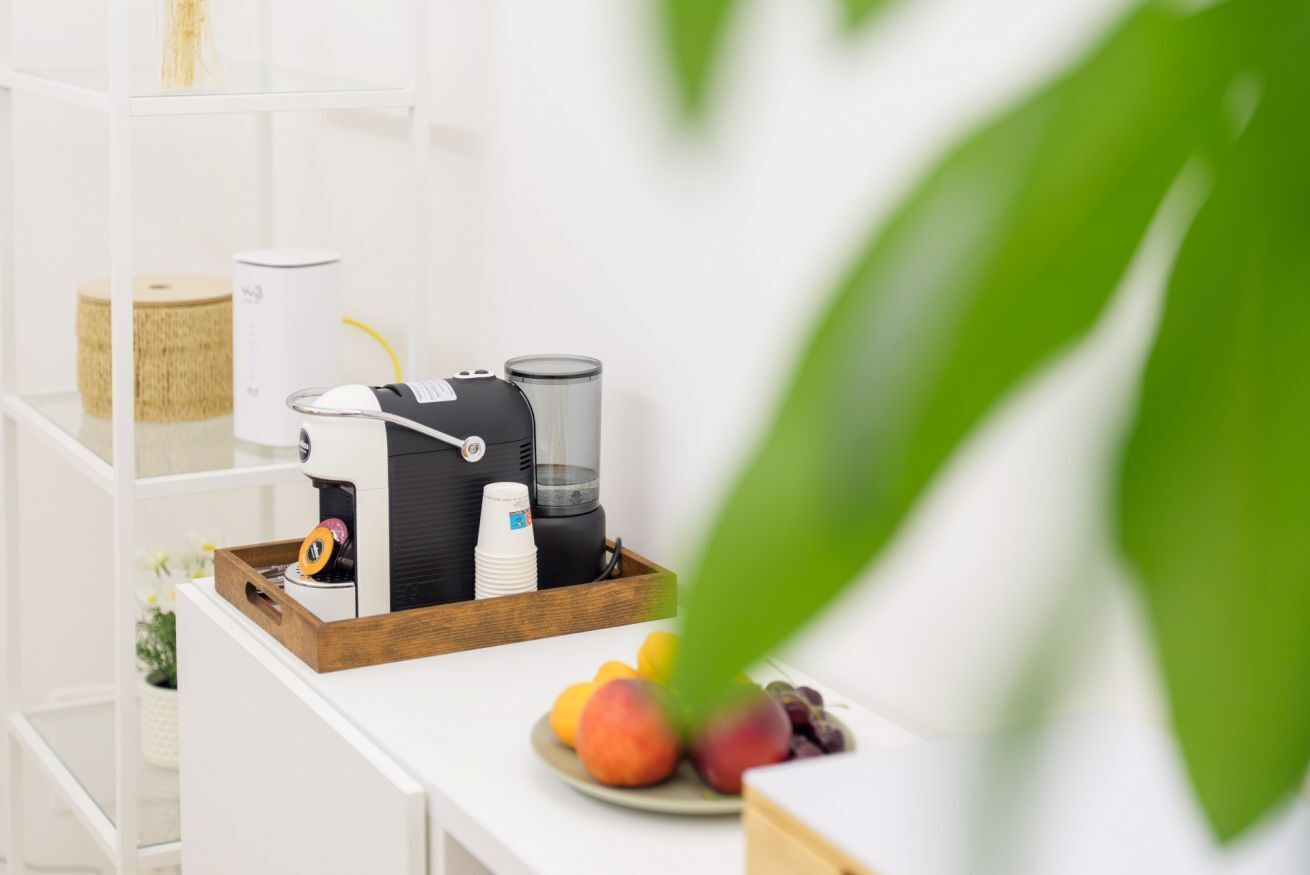 Un coin cuisine équipé d’une machine à café, d’un mixeur et d’un plateau de fruits posé sur le comptoir.