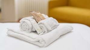 Une serviette blanche, soigneusement pliée, et une bouteille de lotion sont posées sur un lit.