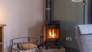 Et værelse med en brændeovn, en stol, en lampe og en opbevaringskurv.