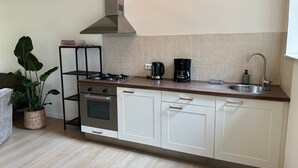 Eine Küche mit weißen Schränken, einer Edelstahl-Spüle, einem Gasherd, einer Dunstabzugshaube und einer Kaffeemaschine.
