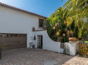 A white building with a tiled roof, a wooden garage door, and a paved driveway. - Private Serene Florida Estate Near Beaches (Fort Myers)
