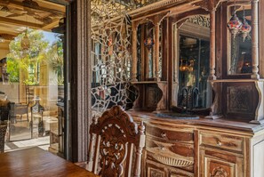 Une pièce comprenant une commode en bois, un miroir et une porte vitrée donnant sur un balcon aménagé avec du mobilier d’extérieur.