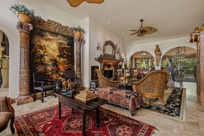 A spacious living room with a large painting, ornate furniture, and a ceiling fan. - Private Serene Florida Estate Near Beaches (Fort Myers)