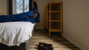 Una habitació amb un llit, una prestatgeria de fusta i un parell de sabates a terra.