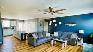 A spacious living area with a wooden floor, grey sofas, a coffee table, and a ceiling fan. - 1 Block to the Beach - 4BR - Fenced Yard - Sleeps 8 - Port Clinton - Lake Erie (Port Clinton)