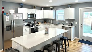 A modern kitchen with white cabinets, stainless steel appliances, a central island, and a view to the outside. - 1 Block to the Beach - 4BR - Fenced Yard - Sleeps 8 - Port Clinton - Lake Erie (Port Clinton)
