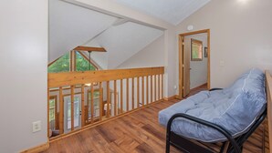 A room with a wooden floor, a bed with a grey mattress, a wooden railing, and a view of a balcony with a wooden railing. - Welcome to Biltmore Escape, your perfect Sevierville retreat nestled in the hear (Sevierville)