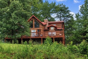 Eine Hütte mit einer Terrasse, umgeben von dichtem Wald.