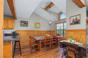 A kitchen with wooden cabinets, a dining table, and a hanging light fixture. - Welcome to Biltmore Escape, your perfect Sevierville retreat nestled in the hear (Sevierville)